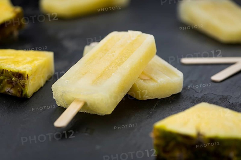 Homemade Pineapple Popsicles on a slate slab (selective focus, close-up shot)