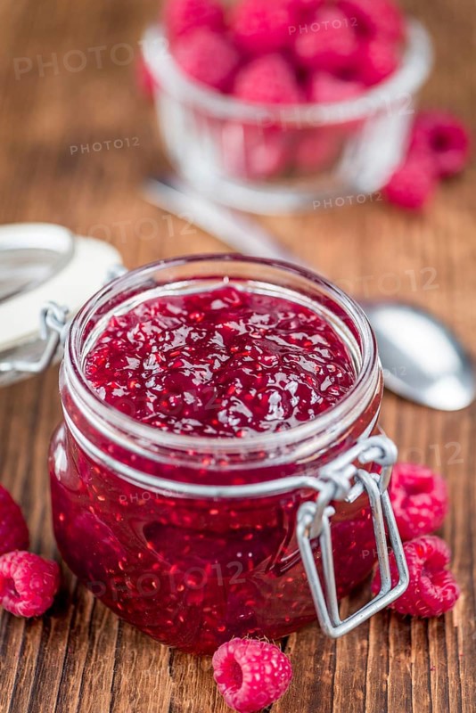 Homemade Raspberry Jam on an wooden table as detailed close-up shot, selective focus