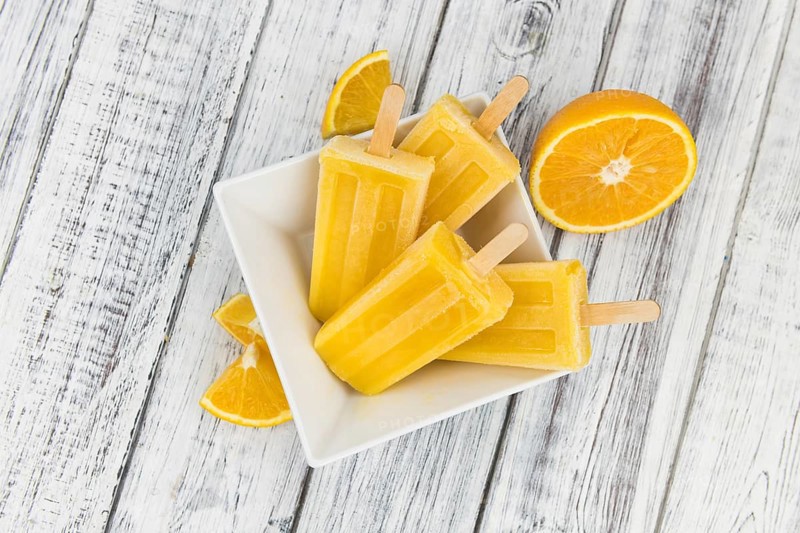 Orange Popsicles (selective focus, close-up shot) on a vintage background