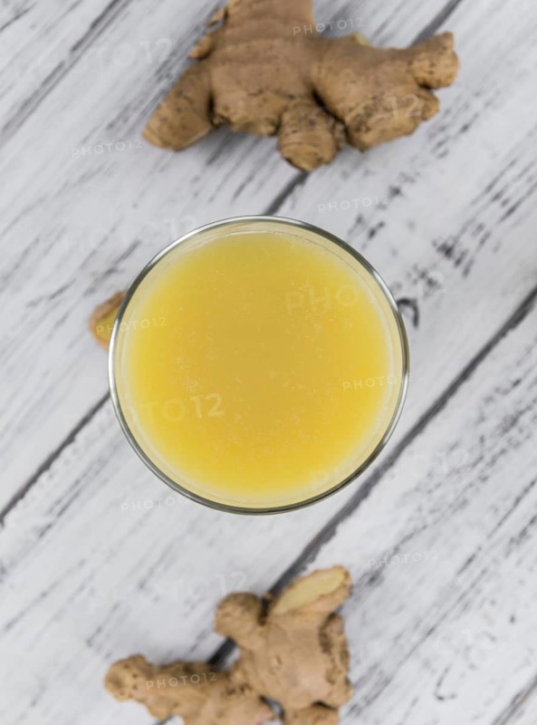 Healthy Ginger Sap on a wooden table as detailed close-up shot (selective focus)