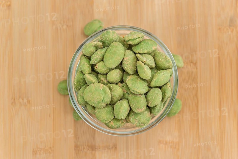 Peanuts (with Wasabi flavor) on an old wooden table as detailed close-up shot (selective focus)