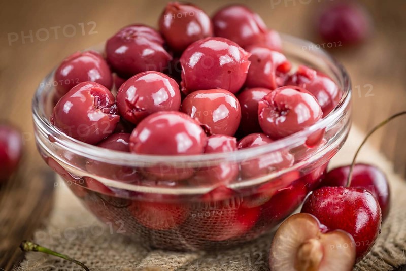 Preserved Cherries on an old wooden table as detailed close-up shot, selective focus