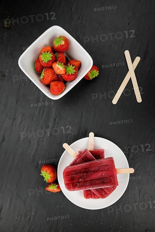 Homemade Strawberry Popsicles (close-up shot, selective focus) on vintage background