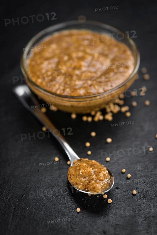 Portion of Mustard (sweet) as detailed close up shot on a slate slab (selective focus)