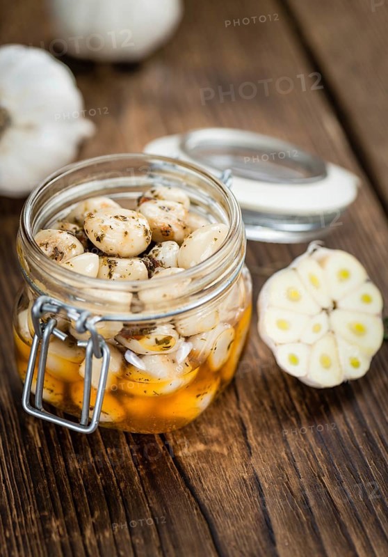 Garlic (preserved) as high detailed close-up shot on a vintage wooden table (selective focus)