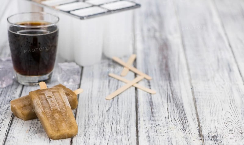Fresh made Cola Popsicles on wooden background (selective focus, close-up shot)