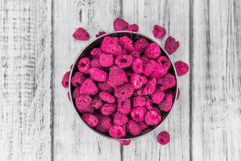 Raspberries (dried) as high detailed close-up shot on a vintage wooden table, selective focus