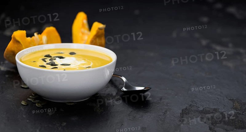 Portion of fresh made Pumpkin Soup (close-up shot) on rustic background