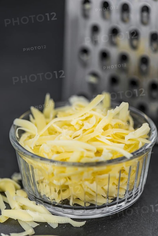 Homemade Grated Cheese (close-up shot) on a vintage slate slab