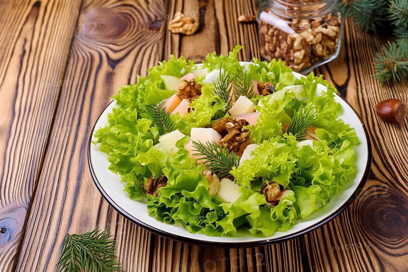 A fresh salad on a wooden table with nuts and fir branches. Healthy and natural meal, AI generated, AI generated