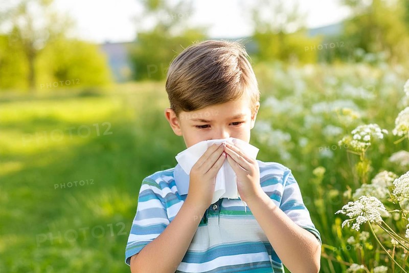 A boy in a polka dot shirt stands in a meadow of flowers and blows his nose with a handkerchief during an allergy attack, AI generated, AI generated