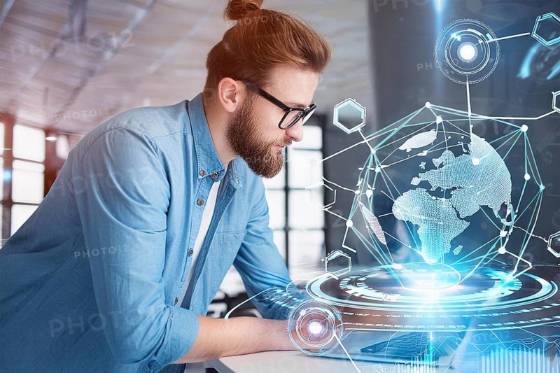 A man in a modern office works on a laptop with a holographic globe and technological graphics in the background, AI generated, AI generated