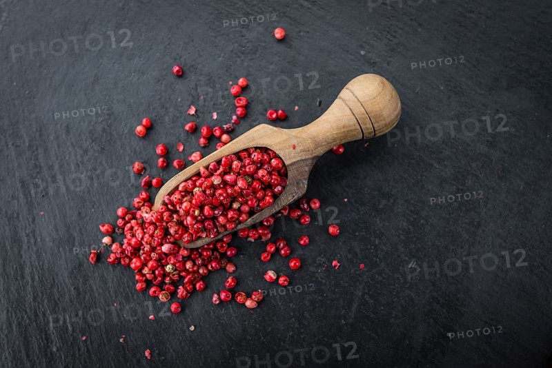 Portion of Pink Peppercorns as detailed close up shot on a slate slab, selective focus