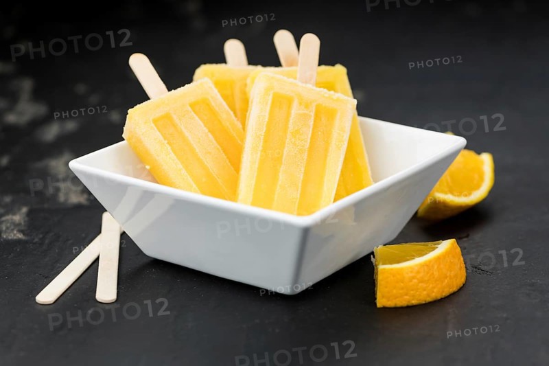 Orange Popsicles (selective focus, close-up shot) on a vintage background