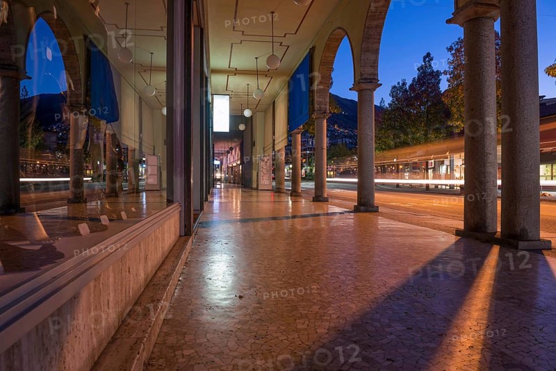 Shopping Street with Shops and Reflection Below Archway in Dusk and Long Exposure in City of Locarno, Ticino, Switzerland, Europe