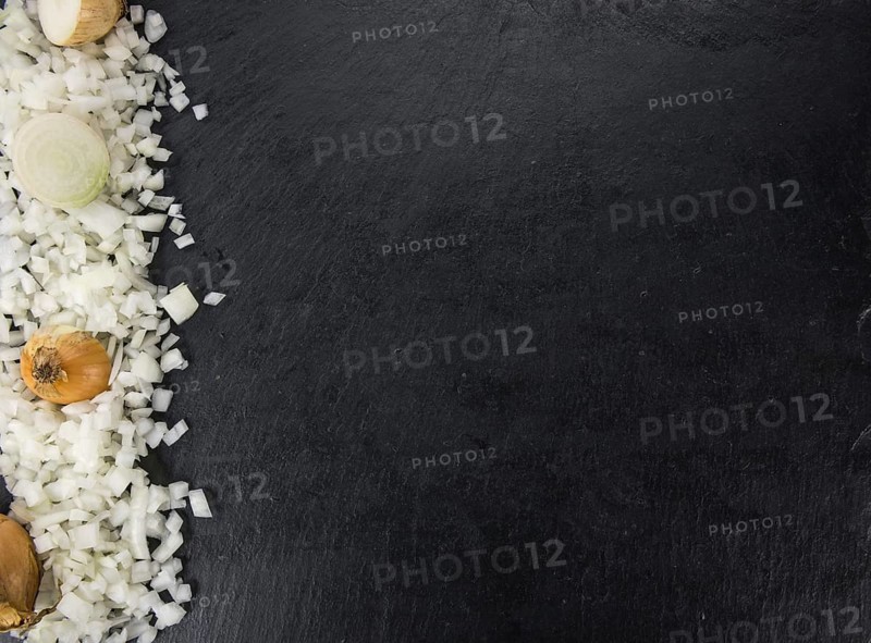 Some White Onions (dices) on a slate slab as detailed close-up shot, selective focus