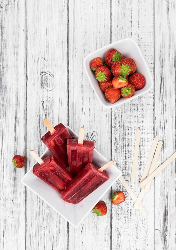 Homemade Strawberry Popsicles (close-up shot, selective focus) on vintage background