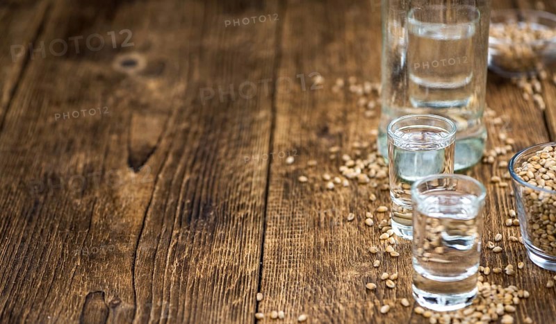 Wooden table with Wheat Liqueur (detailed close-up shot, selective focus)