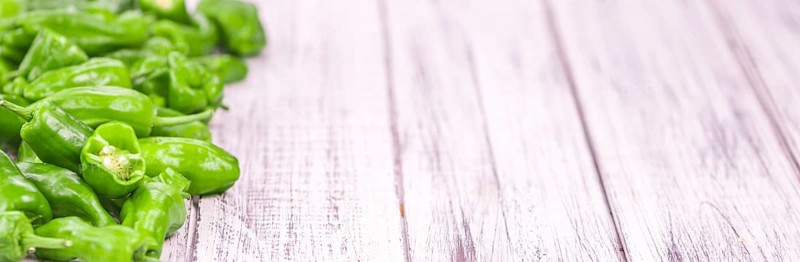 Raw Pimientos on rustic wooden background as close-up shot