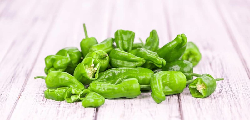 Raw Pimientos on rustic wooden background as close-up shot