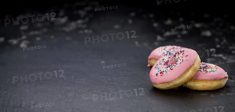 Portion of pink glazed Donuts (detailed close-up shot)