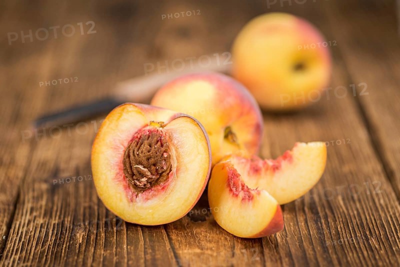 Fresh Peaches as high detailed close-up shot on a vintage wooden table, selective focus