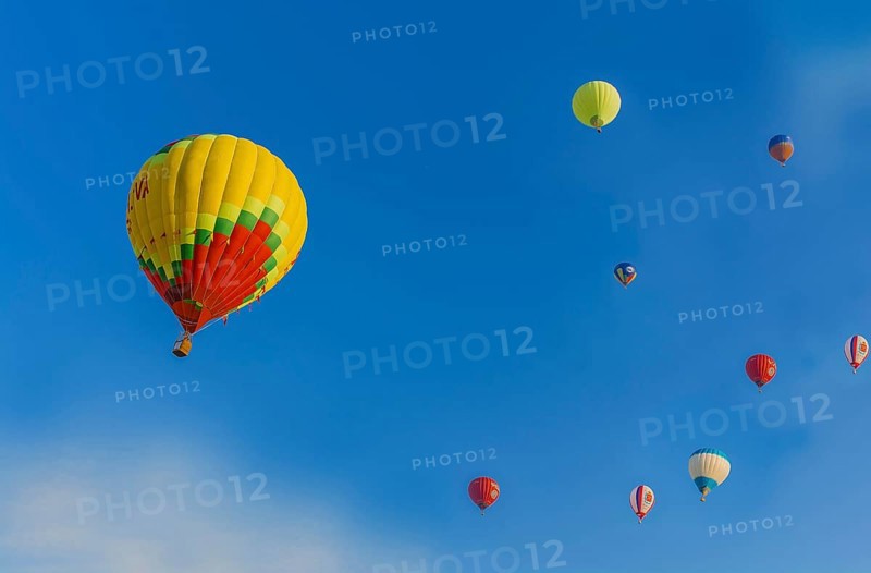 Several hot air balloons of various colors floating in a clear blue sky, Belarus, Minsk, Europe