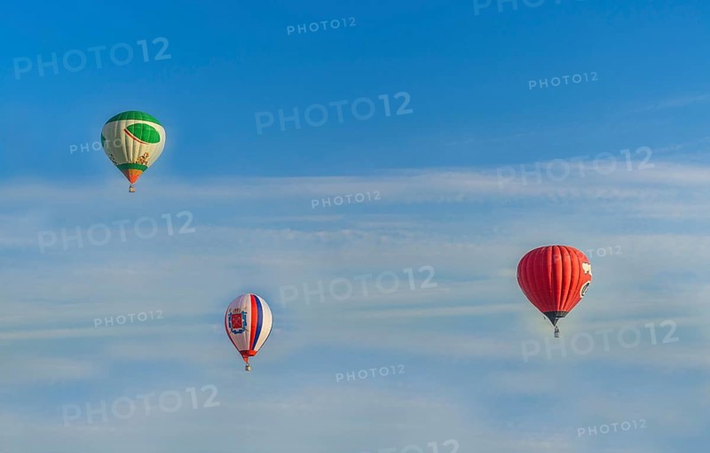 Hot air balloons in different colors soaring through a blue sky with light clouds, Belarus, Minsk, Europe