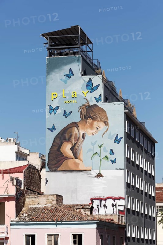 Child among butterflies looking at small plant, symbol of nature, mural at Play Hotel by street artist M. Koan, Athens, Greece, Europe