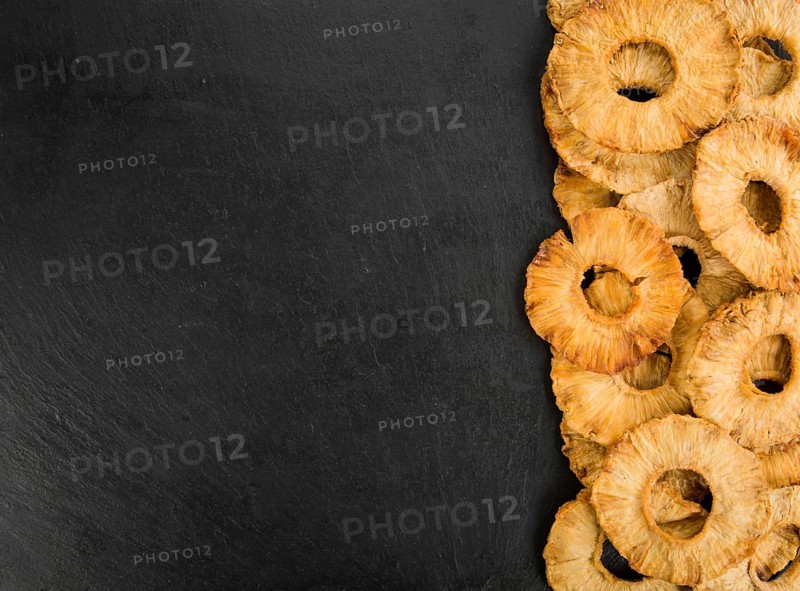 Portion of Dried Pineapple Rings on a rustic slate slab, selective focus, close-up shot