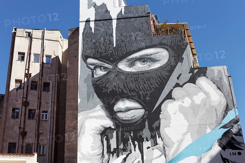 Portrait of a masked man with a clenched fist, Apocalypse now, mural in scarlet white by Greek street artist INO, Psirri neighbourhood, Athens, Greece, Europe