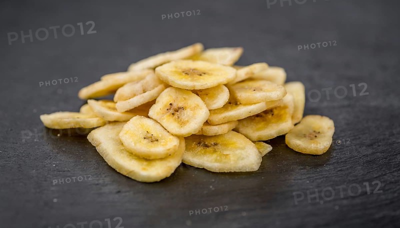 Portion of Dried Banana Chips on a rustic slate slab, selective focus, close-up shot