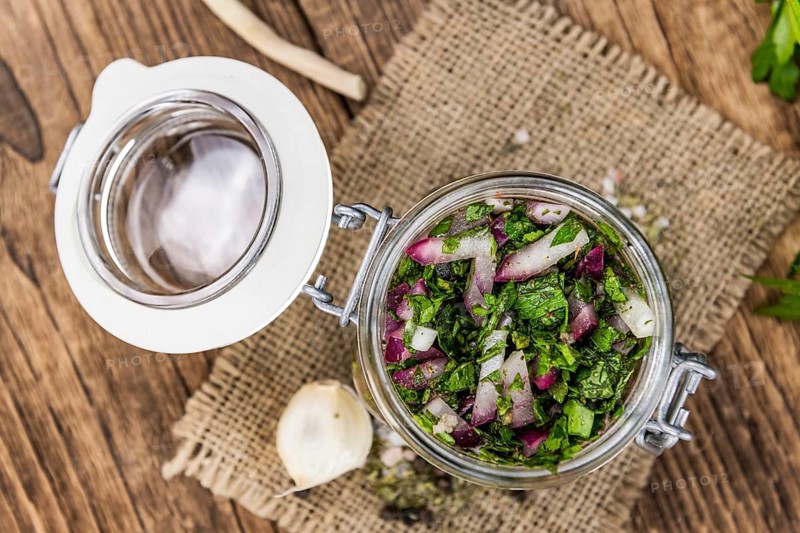 Healthy homemade Chimichurri on a wooden table as detailed close-up shot (selective focus)
