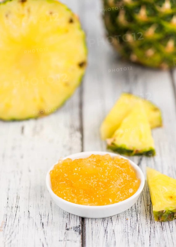 Pineapple Jam as high detailed close-up shot on a vintage wooden table, selective focus