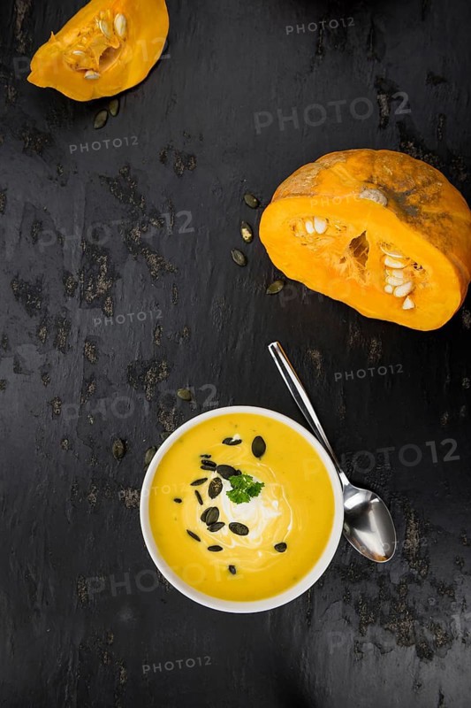 Portion of fresh made Pumpkin Soup (close-up shot) on rustic background