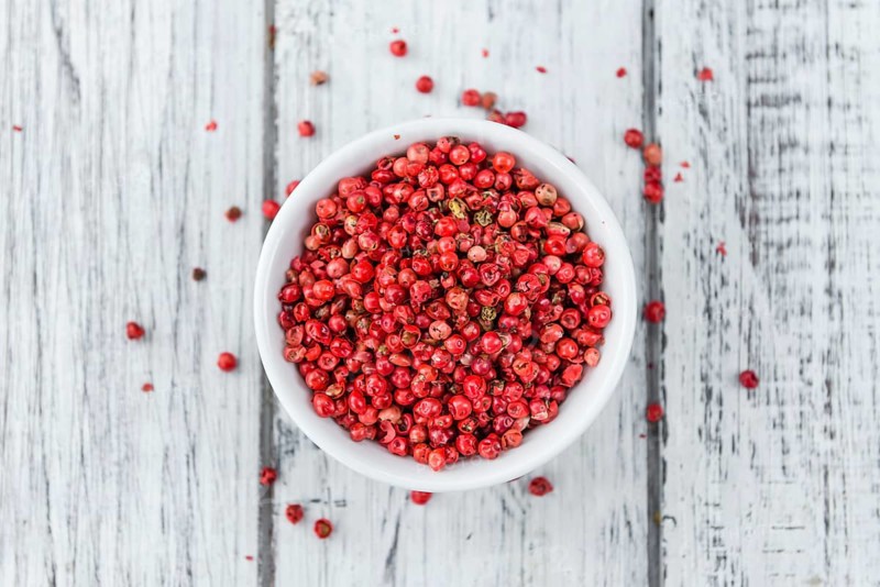 Pink Peppercorns on an old wooden table as detailed close-up shot, selective focus
