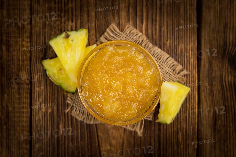 Pineapple Jam as high detailed close-up shot on a vintage wooden table, selective focus