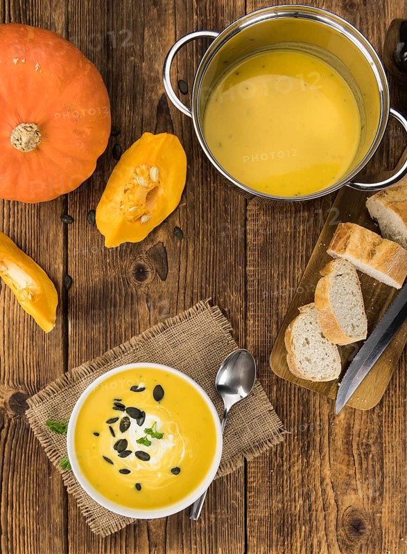 Portion of fresh made Pumpkin Soup (close-up shot) on rustic background