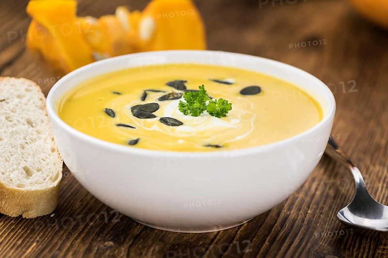 Portion of fresh made Pumpkin Soup (close-up shot) on rustic background