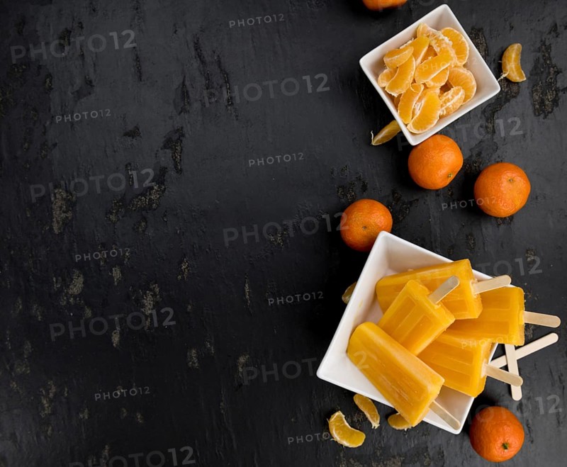 Slate slab with homemade Tangerine Popsicles (selective focus) as detailed close-up shot