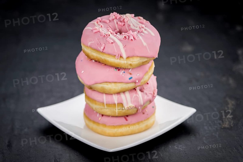 Portion of pink glazed Donuts (detailed close-up shot)
