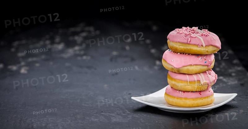 Portion of pink glazed Donuts (detailed close-up shot)
