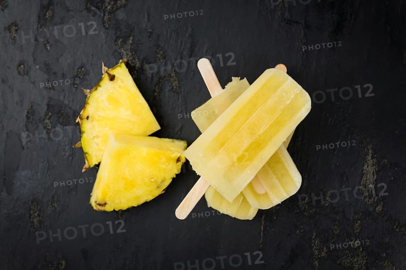 Some homemade Pineapple Popsicles (selective focus) on a rustic background