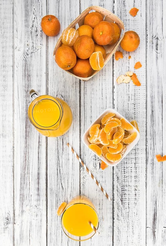 Wooden table with fresh homemade Tangerine Juice (close-up shot, selective focus)