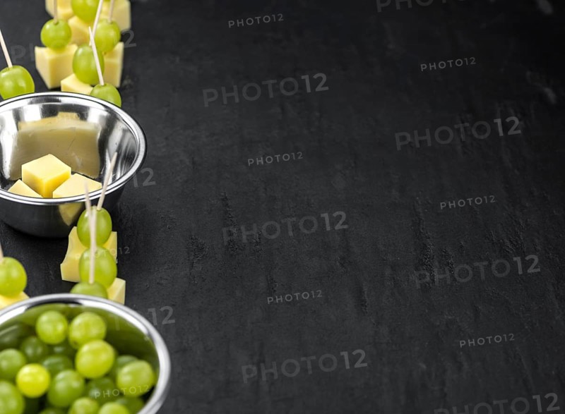 Cheese blocks with grapes as close-up shot on a vintage looking slate slab (selective focus, partyfood)