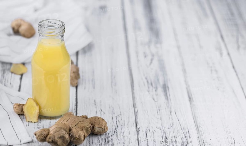 Healthy Ginger Sap on a wooden table as detailed close-up shot (selective focus)
