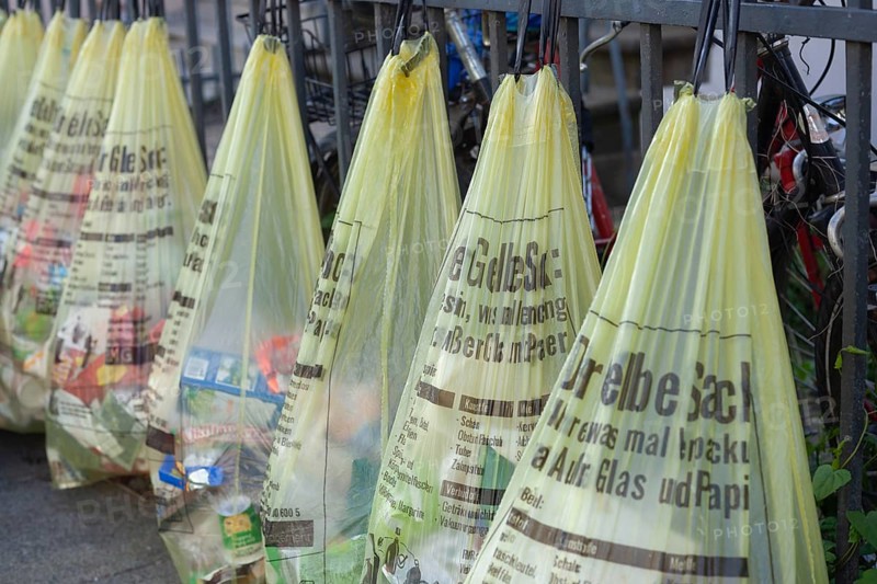 Yellow bags for plastic waste, hanging on a garden fence in front of a house entrance, waste separation, Bremen, Germany, Europe