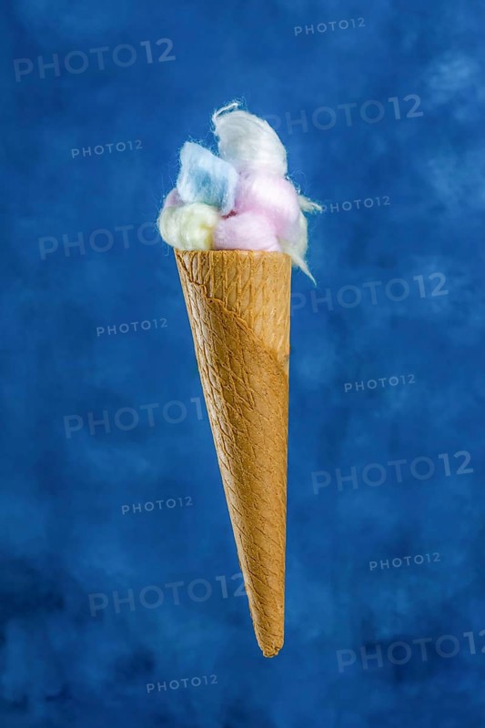 Different colored cotton balls in an ice cream cone on a blue background