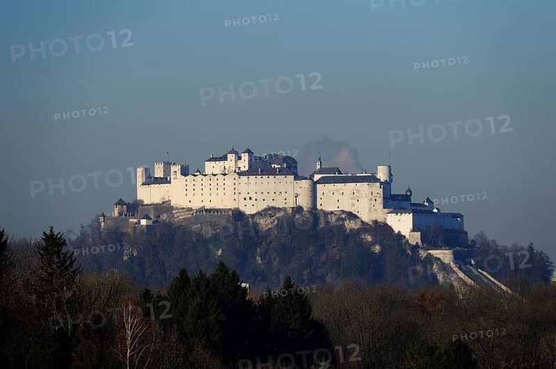 Medieval castle on a wooded hill, surrounded by trees and with a clear sky, Hohensalzburg Fortress, Salzburg