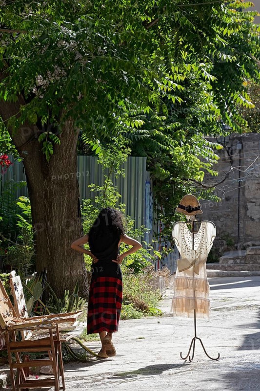 Clothes rack with summer dress in the morning light, placed in front of a fashion boutique, woman waiting for customers, Plaka neighbourhood, Athens, Greece, Europe